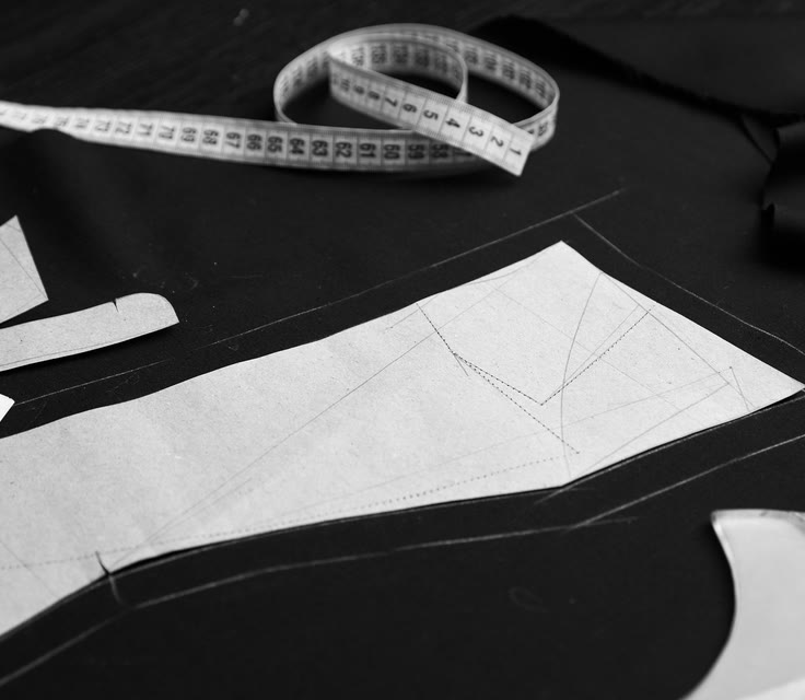 Pattern pieces and a measuring tape laid out on black fabric