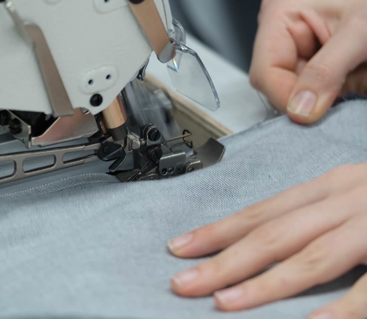 A seam closing under the needle, hands guiding the cloth