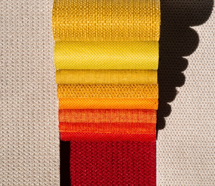 Knitted swatches laid out from yellow through to red